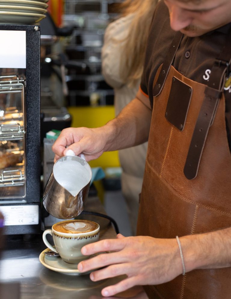Specialty Coffee bei Savos in München Ein Barista bereitet einen Cappuccino zu. Perfekt geschäumte Milch zu dem Specialty Coffee mit Bohnen aus Kolumbien